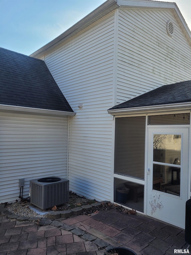 view of side of home featuring roof with shingles and central air condition unit