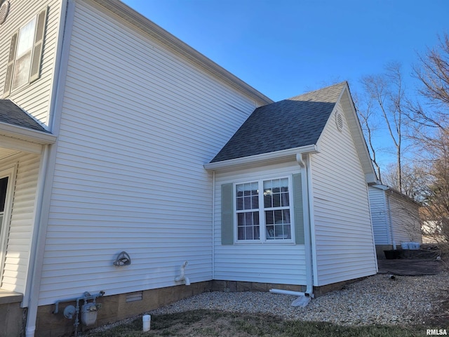 view of home's exterior with a shingled roof and crawl space