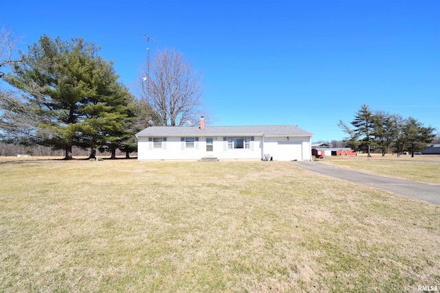 view of front of house featuring a front lawn, a chimney, an attached garage, and aphalt driveway