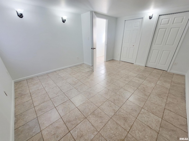 spare room featuring light tile patterned floors and baseboards