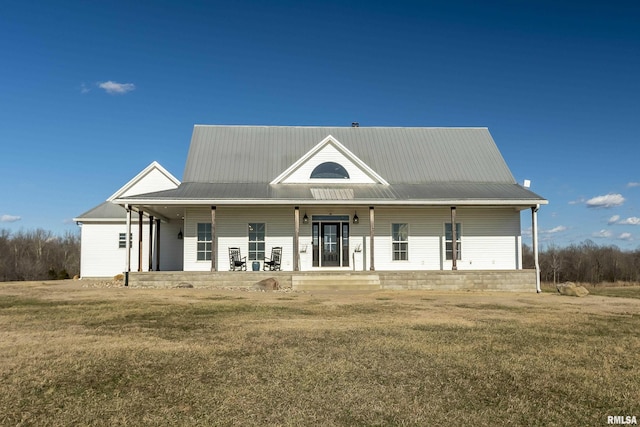 country-style home featuring covered porch, metal roof, and a front yard