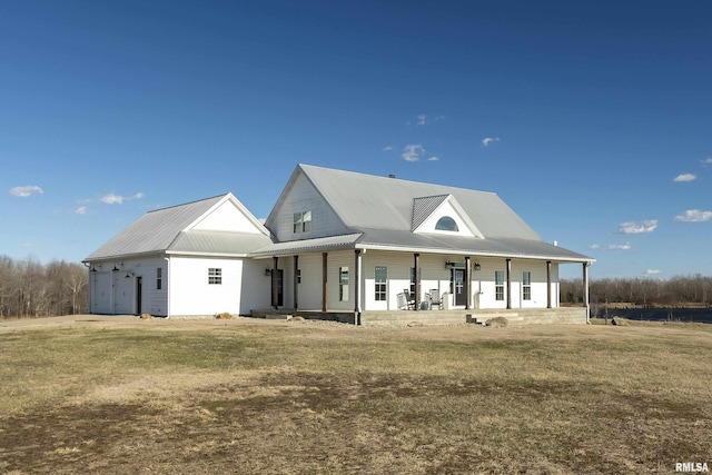 view of front of property with a garage, covered porch, metal roof, and a front yard