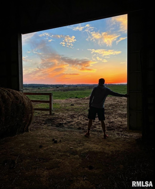 yard at dusk featuring a rural view