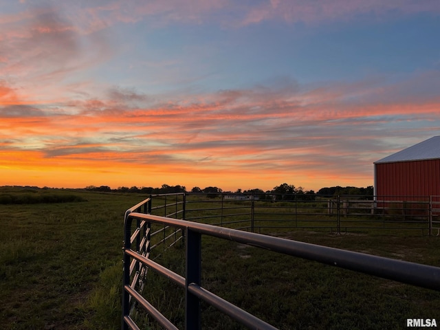 yard at dusk featuring a rural view, an outdoor structure, and fence