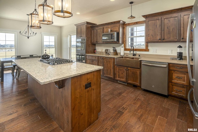 kitchen with stainless steel appliances, dark wood-style flooring, a sink, a healthy amount of sunlight, and a center island