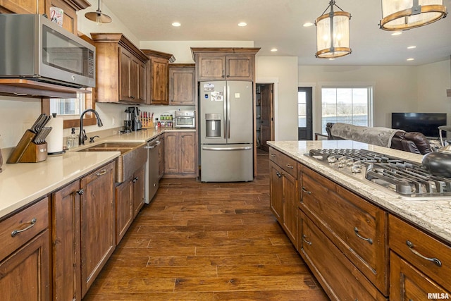 kitchen featuring appliances with stainless steel finishes, dark wood-style flooring, decorative light fixtures, a sink, and recessed lighting