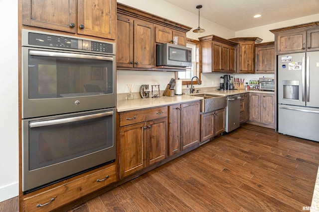 kitchen with stainless steel appliances, recessed lighting, light countertops, dark wood-type flooring, and a sink