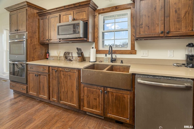 kitchen featuring dark wood-style floors, appliances with stainless steel finishes, light countertops, and a sink