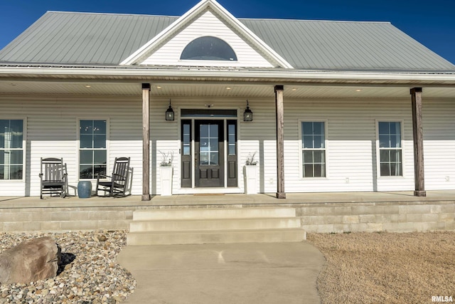 view of exterior entry with covered porch and metal roof