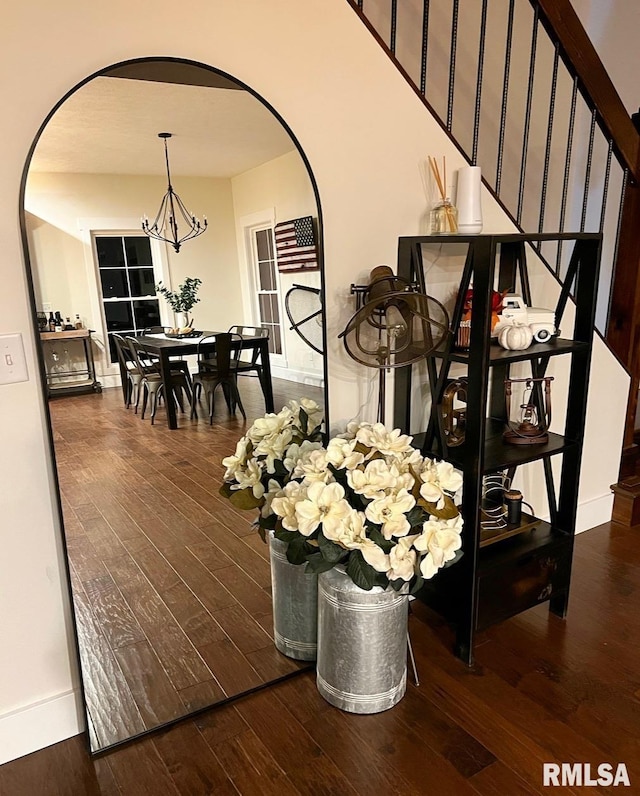 dining room featuring stairs, hardwood / wood-style floors, arched walkways, and an inviting chandelier