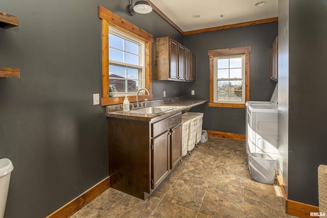 kitchen featuring independent washer and dryer, a sink, and baseboards