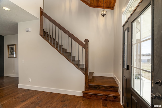 foyer entrance with plenty of natural light, baseboards, and dark wood-type flooring