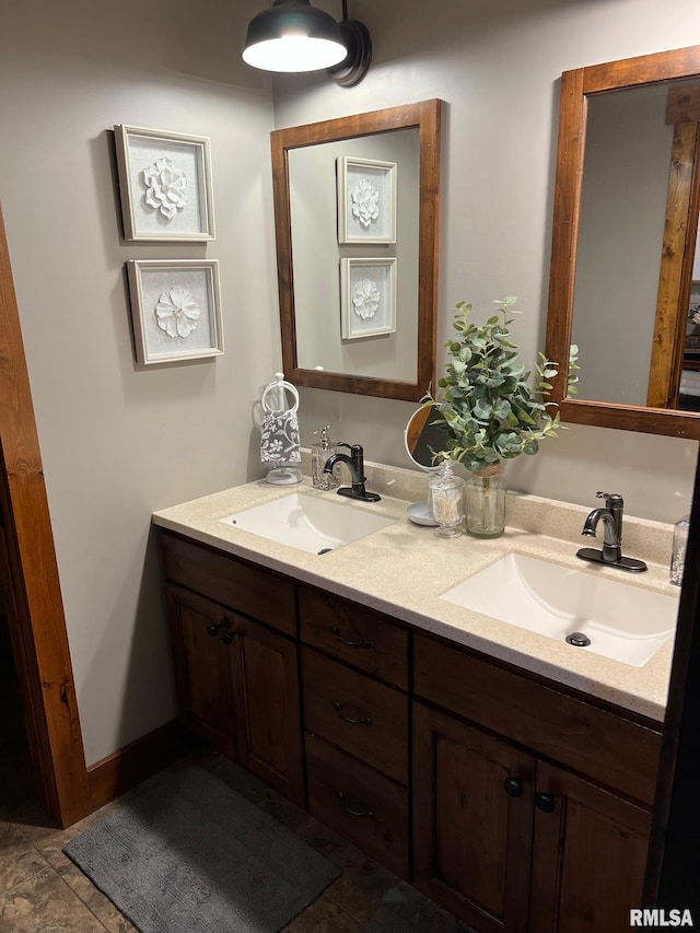 bathroom featuring double vanity, baseboards, and a sink