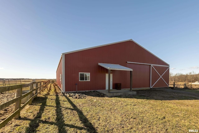 view of pole building with a yard, a rural view, and fence