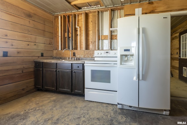 kitchen featuring dark brown cabinetry, white appliances, unfinished concrete floors, wood walls, and a sink