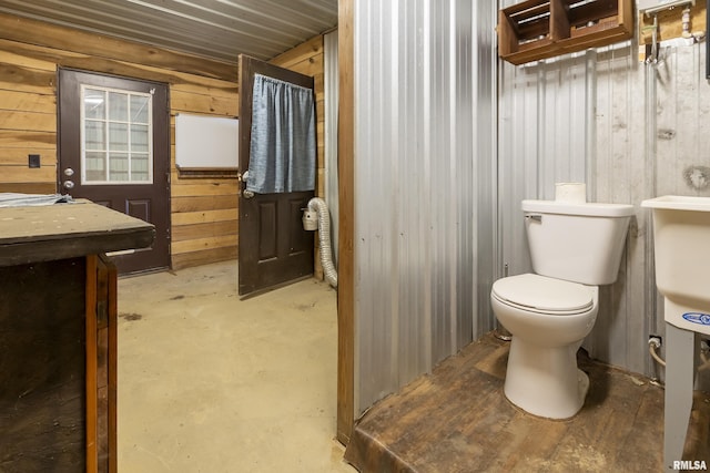 bathroom with toilet and wood walls