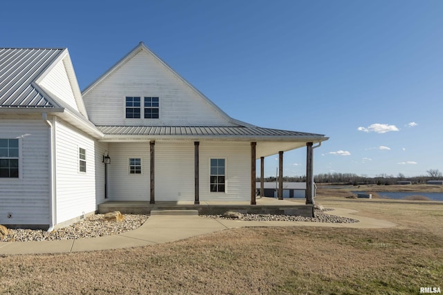 rear view of house with a yard, covered porch, and metal roof