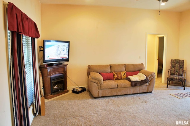 living room featuring a warm lit fireplace, carpet flooring, and baseboards