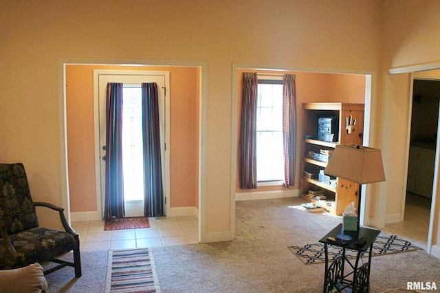 tiled foyer featuring carpet and baseboards