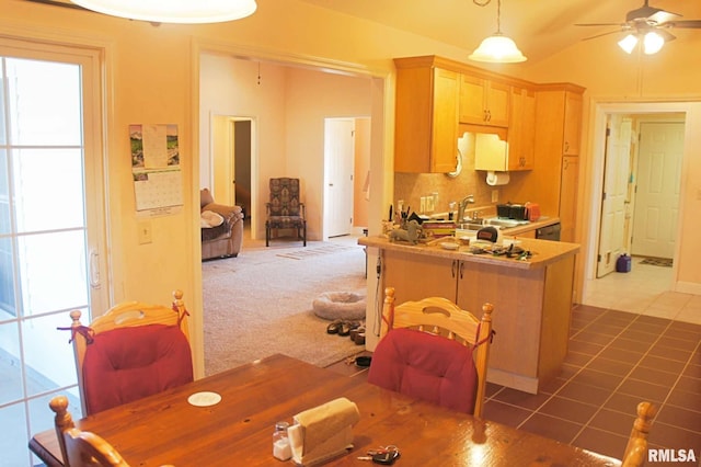 kitchen featuring ceiling fan, a peninsula, a sink, dark tile patterned floors, and backsplash