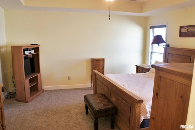 carpeted bedroom featuring a tray ceiling and baseboards