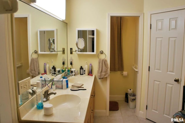 full bathroom featuring double vanity, tile patterned flooring, a sink, and baseboards