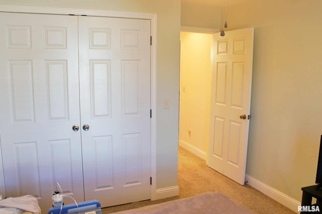 unfurnished bedroom featuring light carpet, baseboards, and a closet