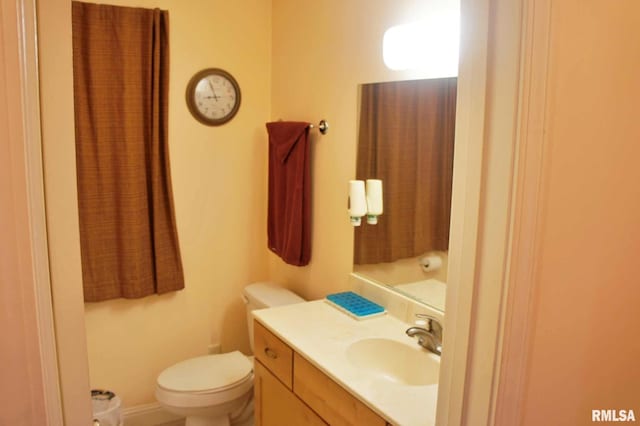 half bath featuring toilet, baseboards, and vanity