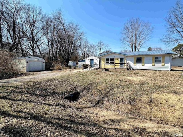 ranch-style home with metal roof, a garage, an outdoor structure, driveway, and a wooden deck