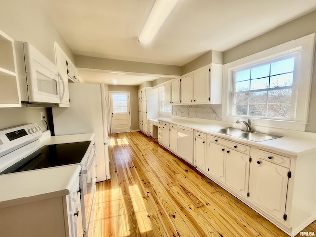 kitchen with light wood finished floors, backsplash, white cabinetry, a sink, and white appliances