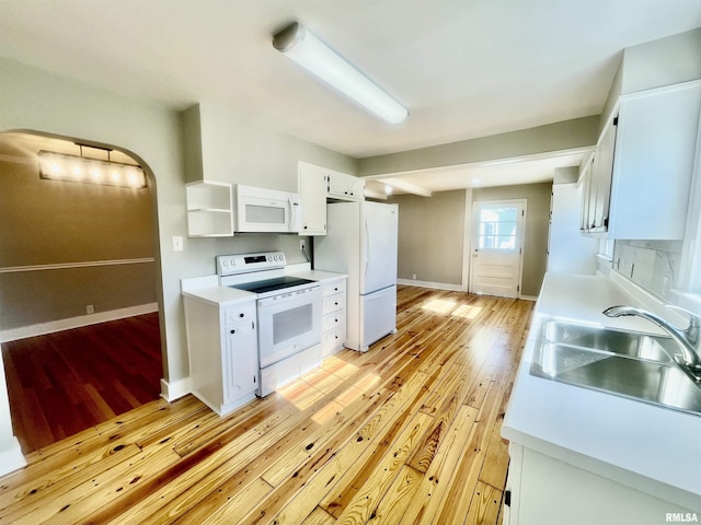 kitchen featuring light countertops, light wood-style floors, white cabinets, a sink, and white appliances