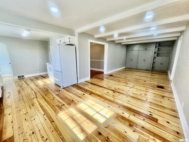 interior space featuring light wood-type flooring, baseboards, visible vents, and freestanding refrigerator