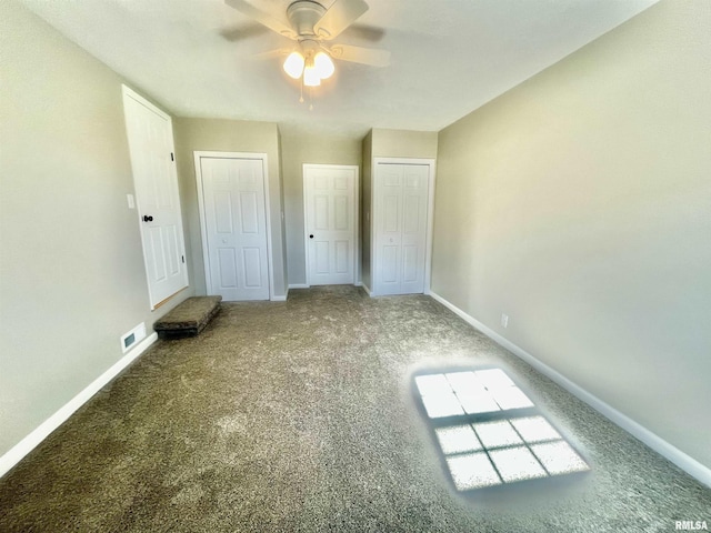 unfurnished bedroom with ceiling fan, carpet floors, visible vents, baseboards, and two closets