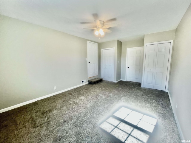 unfurnished bedroom with multiple closets, carpet, ceiling fan, and baseboards