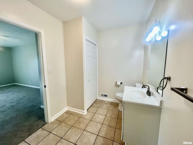 bathroom with toilet, vanity, baseboards, visible vents, and tile patterned floors