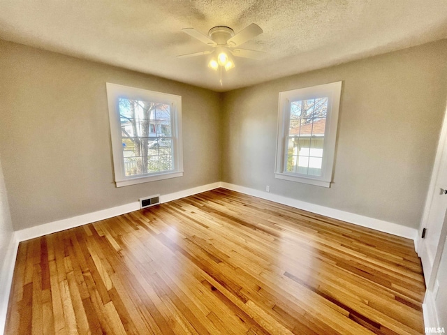 unfurnished bedroom featuring hardwood / wood-style flooring, baseboards, visible vents, and a textured ceiling