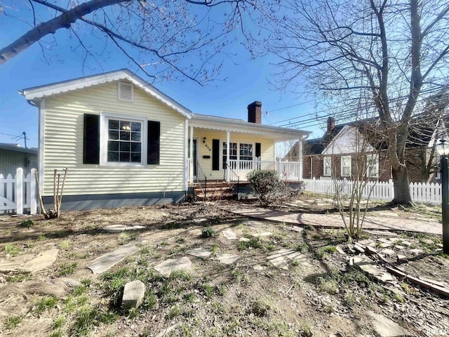 view of front of home featuring a porch, a chimney, and fence