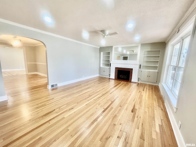 unfurnished living room featuring baseboards, visible vents, a textured ceiling, light wood-type flooring, and a brick fireplace