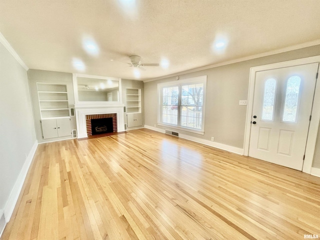 unfurnished living room featuring light wood finished floors, a fireplace, visible vents, and crown molding