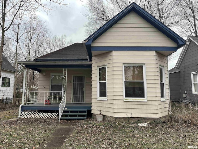 rear view of property with a porch and roof with shingles