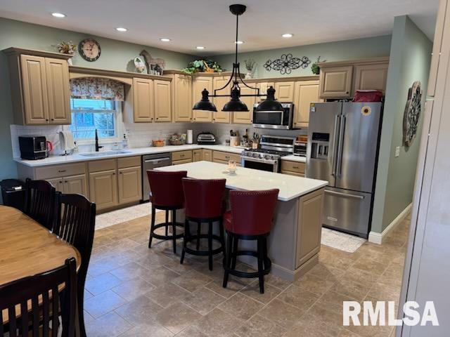 kitchen with a sink, a kitchen island, appliances with stainless steel finishes, light countertops, and decorative backsplash