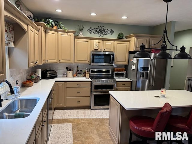 kitchen featuring light countertops, a breakfast bar area, appliances with stainless steel finishes, and a sink