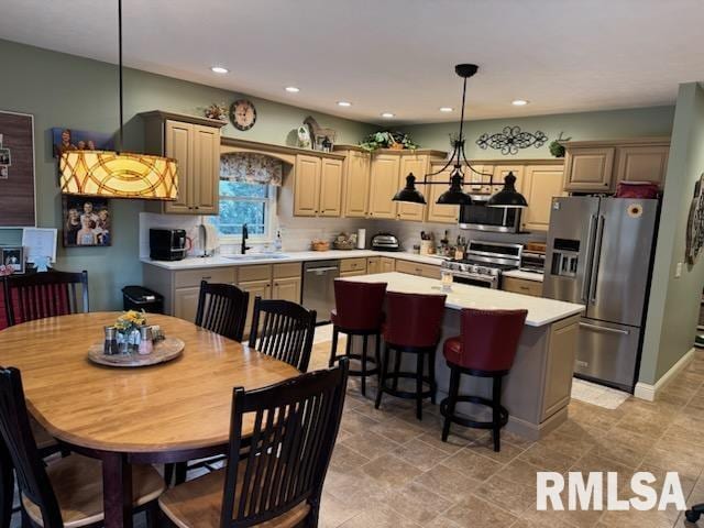 kitchen with high quality appliances, a sink, a kitchen island, light countertops, and hanging light fixtures