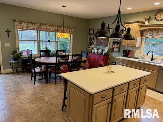 kitchen with light countertops, pendant lighting, a center island, and a sink