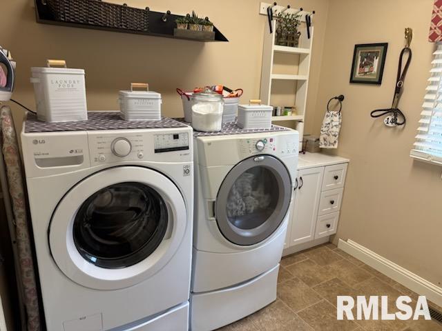 laundry area with baseboards, cabinet space, and separate washer and dryer