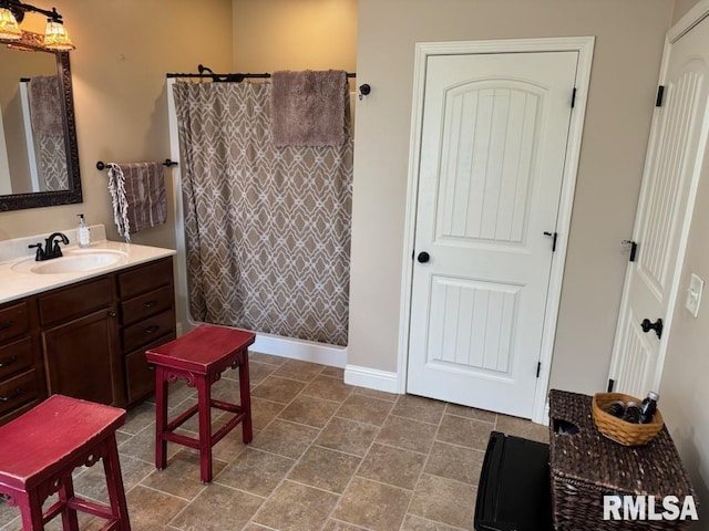 bathroom featuring a shower with shower curtain, baseboards, and vanity