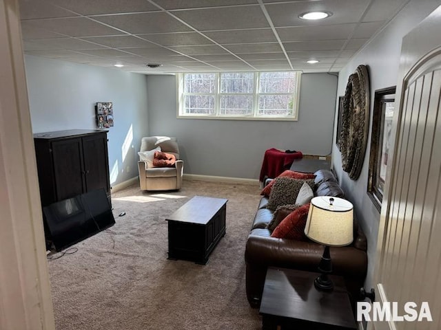 carpeted living room featuring a paneled ceiling and baseboards