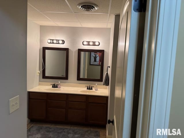 bathroom with double vanity, a drop ceiling, tile patterned floors, and a sink