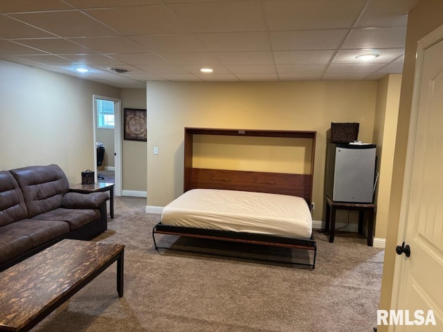 carpeted bedroom featuring a drop ceiling and baseboards