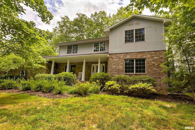 traditional-style house with a front yard, a porch, and brick siding